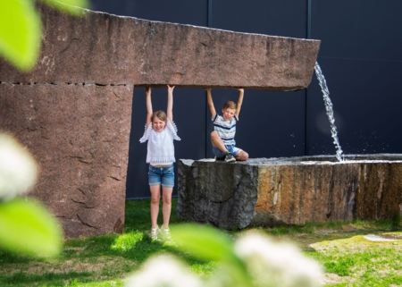 Barn som leker ute i en park med store steiner